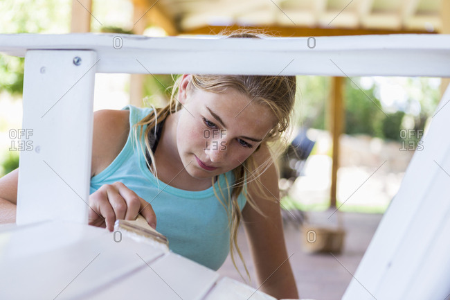 A teenage girl painting  furniture white