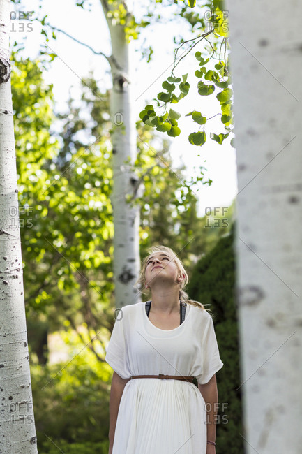A teenage girl in a white dress among trees