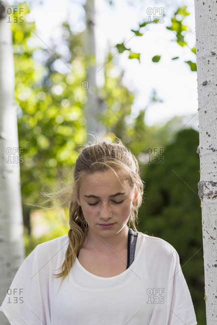 A teenage girl in a white dress among trees