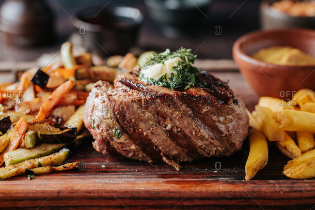 A juicy beef steak on a wooden board with French fries