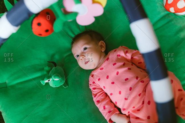 Overhead view of a two month old happy baby girl playing on a child play mat