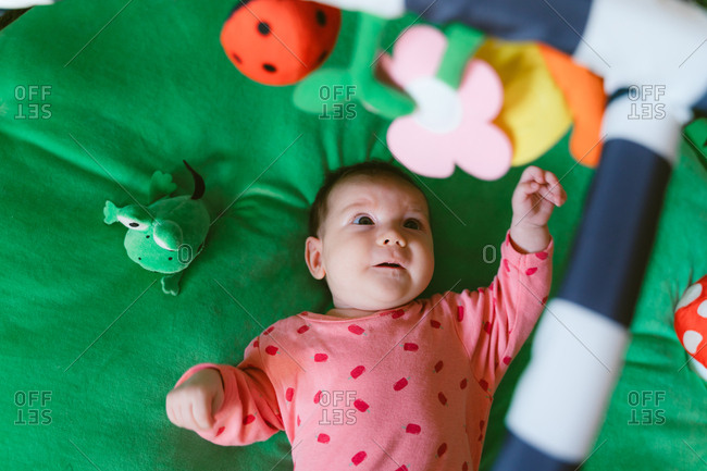 High angle view of a two month old happy baby girl playing on a child play mat