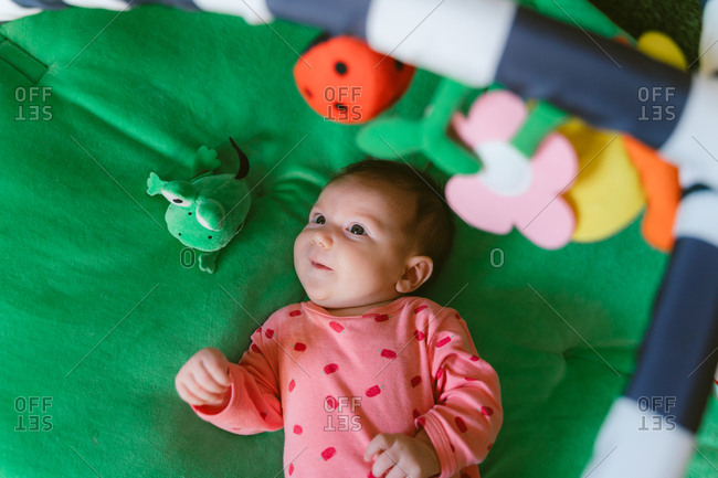 Two month old happy baby girl playing on a child play mat