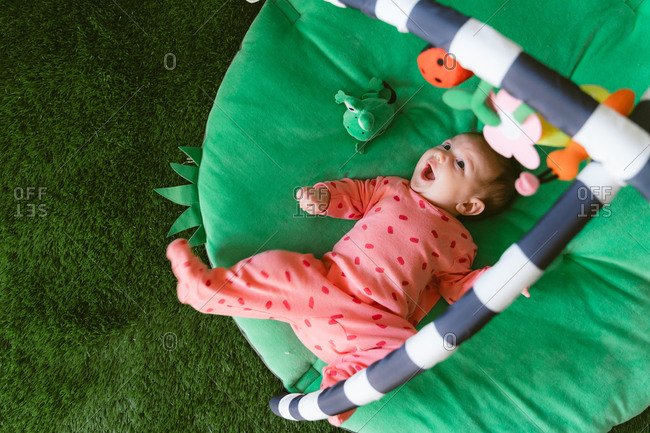Cute little baby girl playing on a child play mat