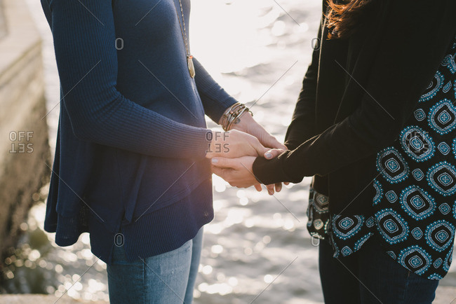 Close up of lesbian couple holding hands by the river, Lisbon, Portugal