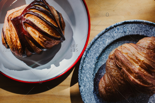 Detail of croissant and pain au chocolat sitting on beautiful plates on a wooden table