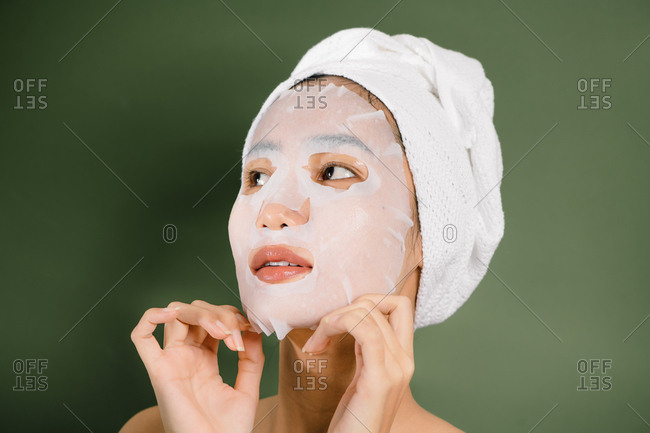 Closeup of Asian woman removing her sheet mask