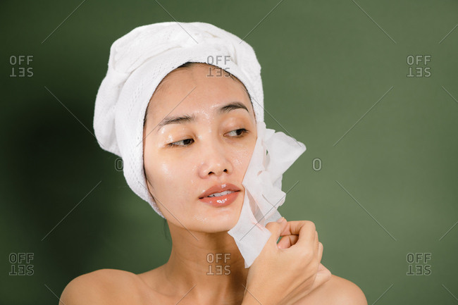Young woman takes off her sheet mask