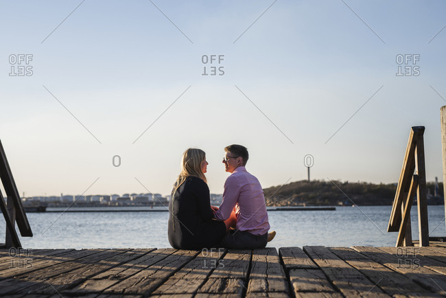 Couple sitting on jetty - Offset