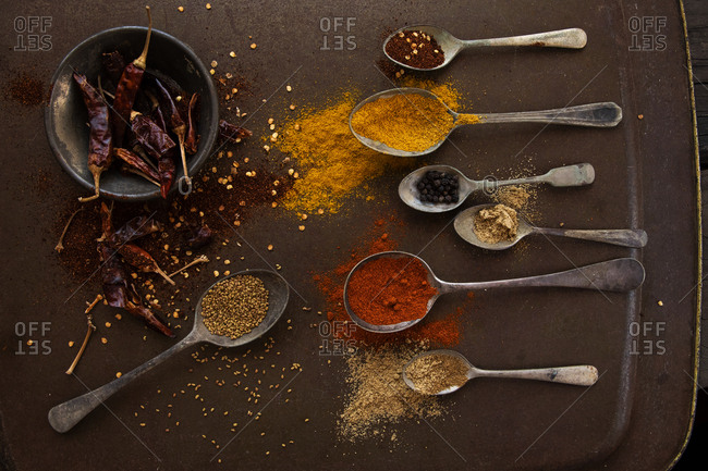 Antique vintage spoons and bowls filled with spices on rustic kitchen tray