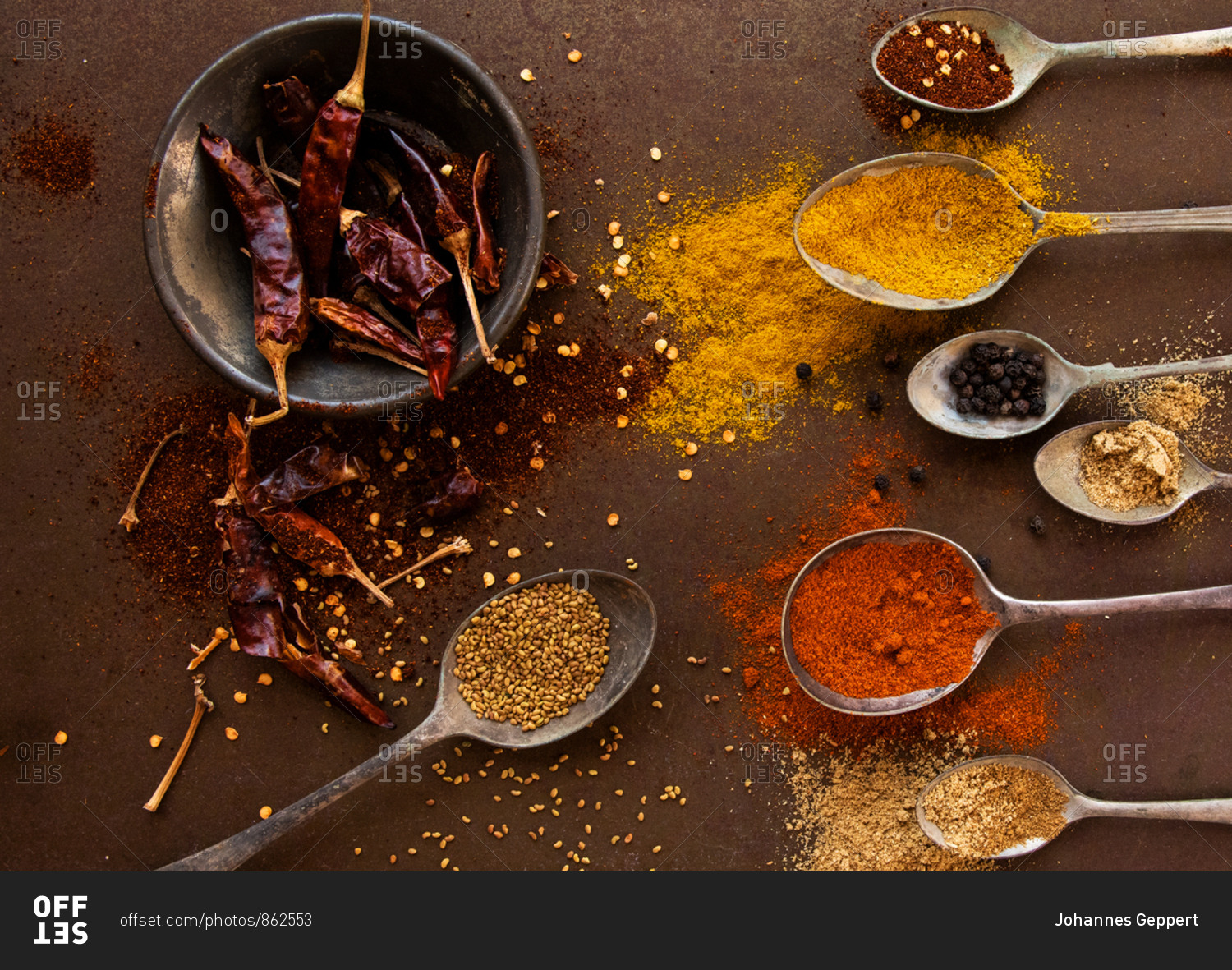 Artistic arrangement of vintage spoons filled with spices and dried chilli peppers