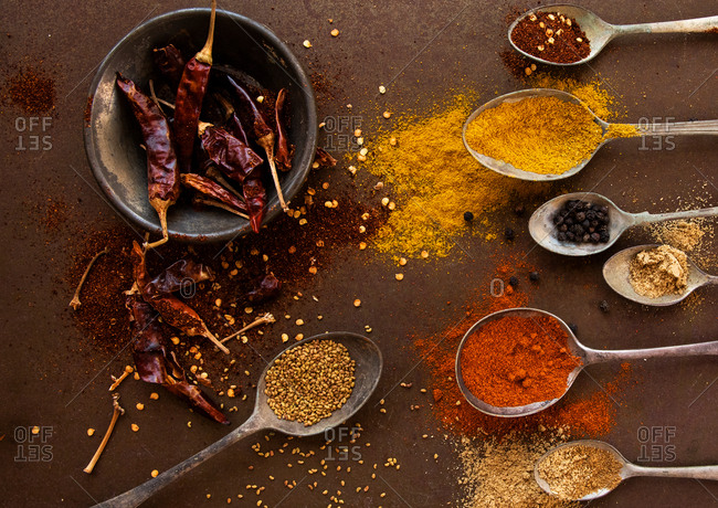 Artistic arrangement of vintage spoons filled with spices and dried chilli peppers