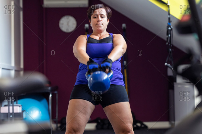 Shot of athletic woman doing exercises with kettlebell at the crossfit gym.