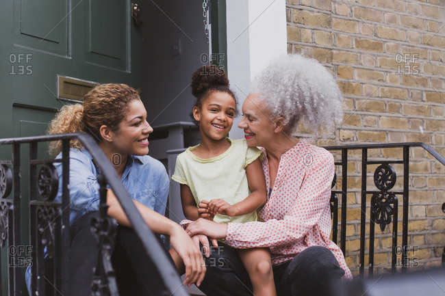 Three generations of women sitting outside family home