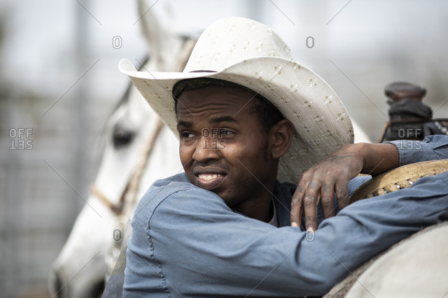 United States, Arizona, Chandler - March 9, 2019: A cowboy leans on his horse at the Arizona Black Rodeo