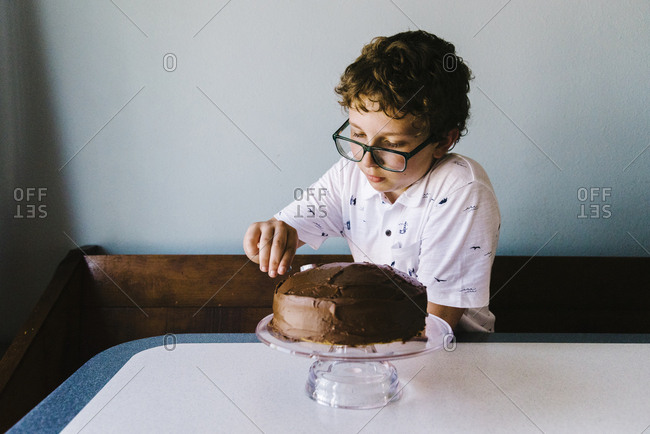 Tween boy frosting his birthday cake with chocolate frosting