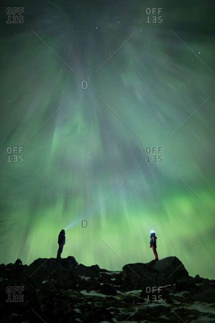 Two people watching the aurora borealise in the night sky