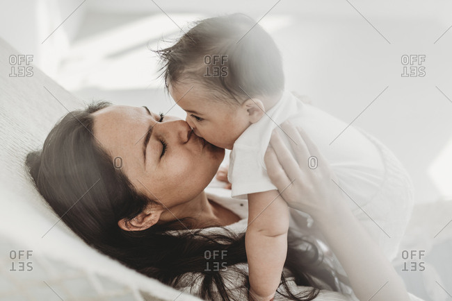 Mother kissing baby daughter hammock in natural light studio