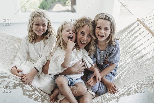 Mother and daughters cuddling on hammock in natural light studio