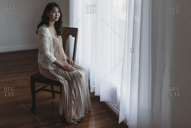 Full length portrait of mother sitting by window in studio