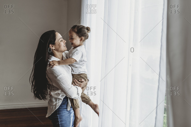 Side view of mother and toddler son playing in natural light studio