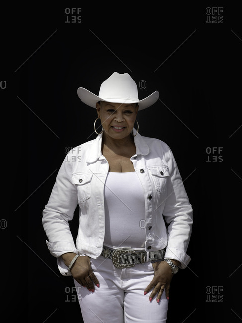 United States, Arizona, Chandler - March 9, 2019: Cowgirl dressed in white against black backdrop
