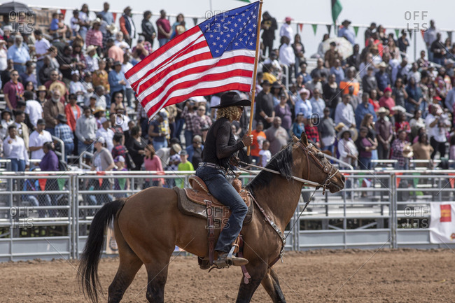 United States, Arizona, Chandler - March 9, 2019: A rider carries an American flag opening the Arizona black rodeo