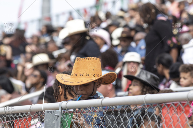United States, Arizona, Chandler - March 9, 2019: A young cowboy sips a straw amongst the crowd at the AZ Black Rodeo