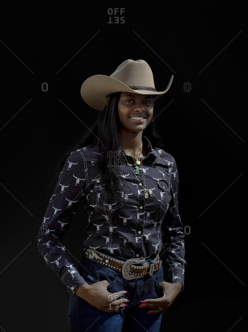 United States, Arizona, Chandler - March 9, 2019: A  rodeo cowgirl poses for a portrait against black in the daylight