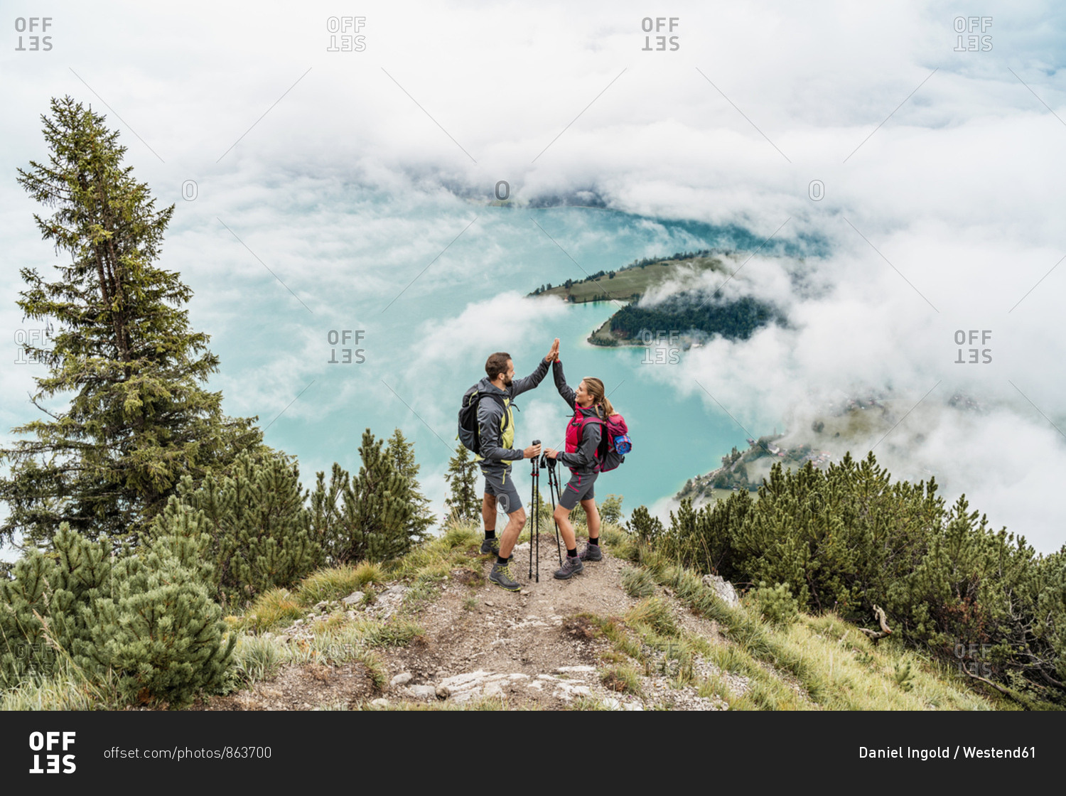 Happy young couple on a hiking trip in the mountains high fiving- Herzogstand- Bavaria- Germany