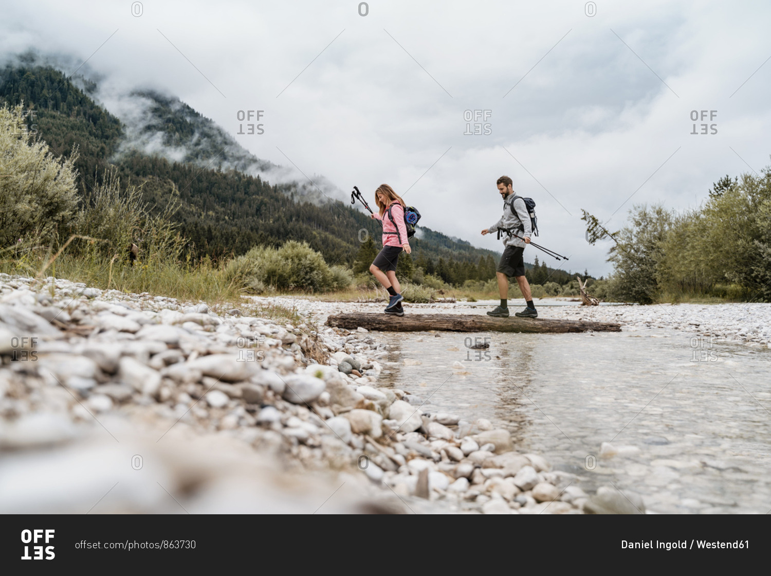 Young couple on a hiking trip crossing river on a log- Vorderriss- Bavaria- Germany