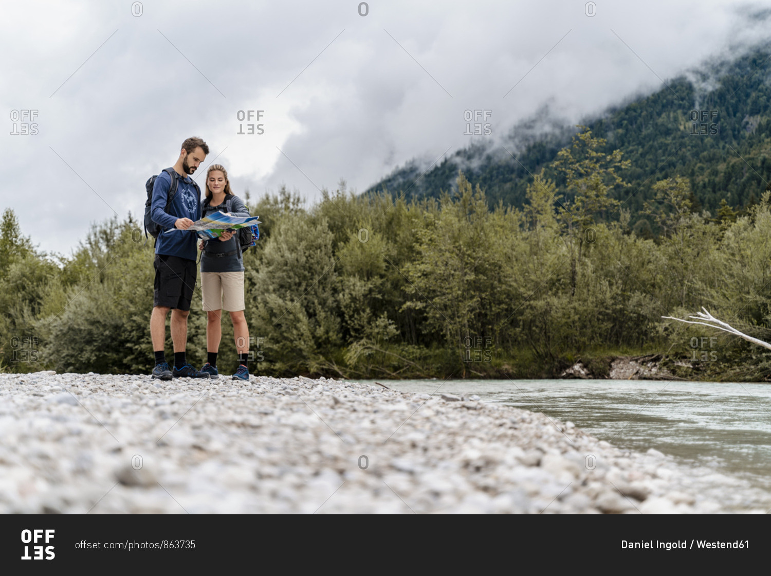Young couple on a hiking trip at riverside reading map- Vorderriss- Bavaria- Germany