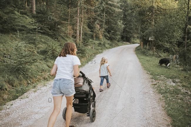 Mother with daughter- stroller and dog walking on forest path
