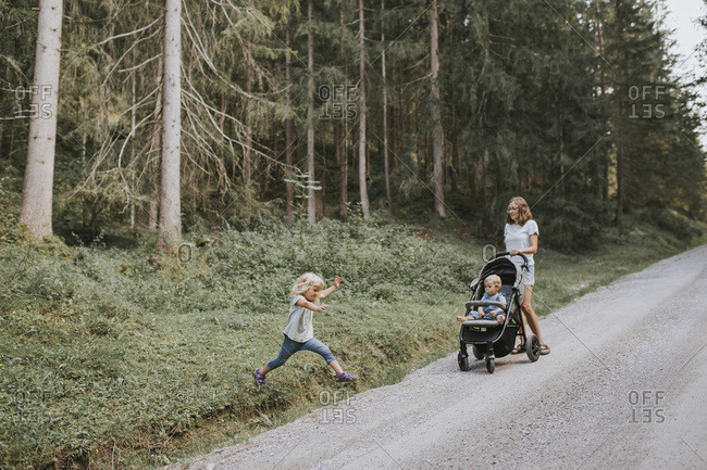 Mother with daughter and baby in stroller in forest