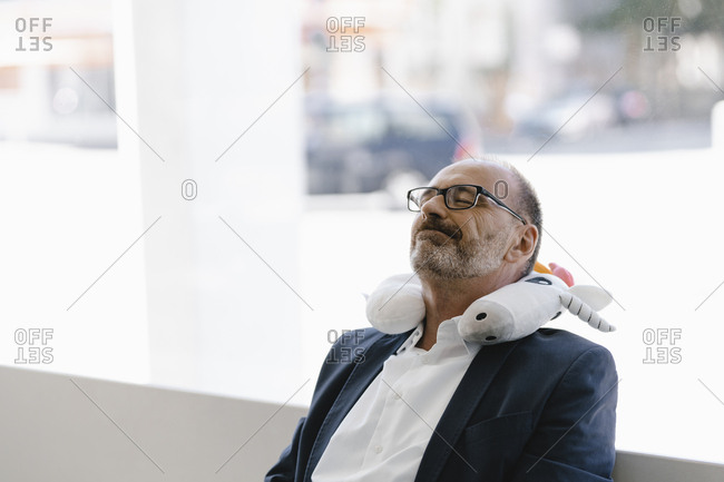 Businessman taking a nap- with a unicorn pillow around his neck