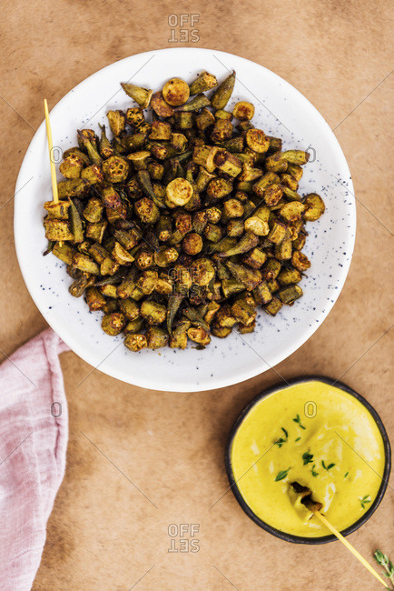 Oven roasted okra chips served with a vegan turmeric tahini dip sauce on the side.