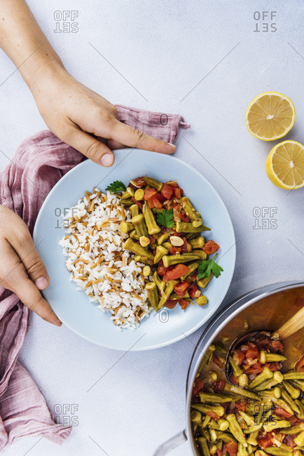 Serving stewed okra and tomatoes with Turkish rice in a light blue bowl
