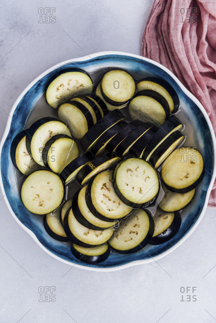 Eggplant slices soaked in salty water in a large bowl