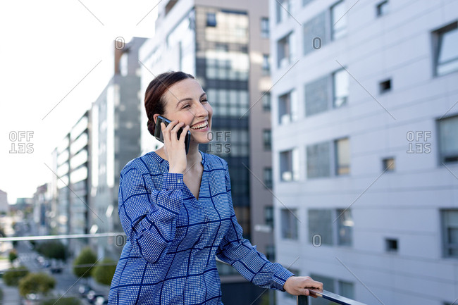 Beautiful businesswoman in blue checkered shirt frowning and looking away while standing on blurred background of modern building on city street