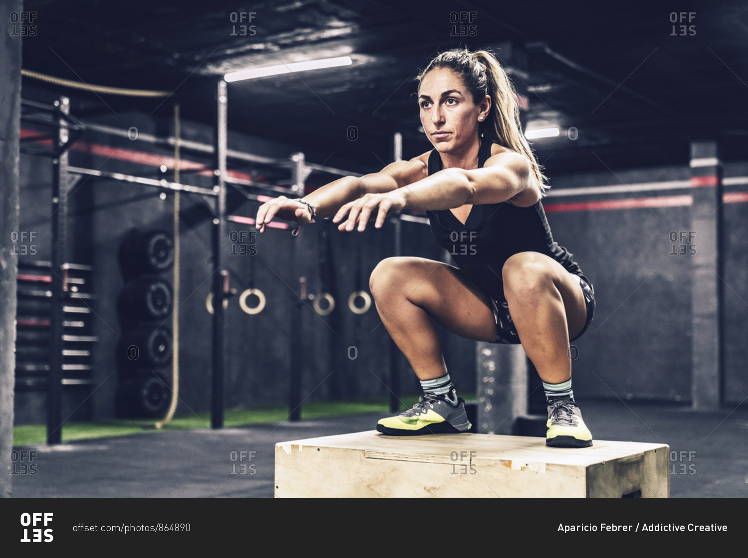 Athletic woman jumping on box to improve stamina in gym