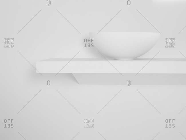 Ceramic bowl placed on simple shelf against white wall in bathroom