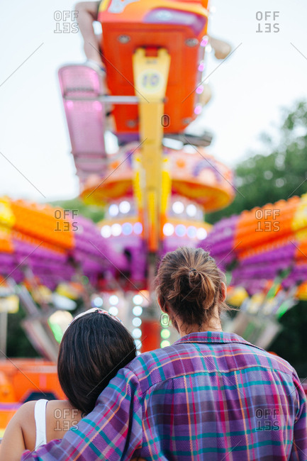 Amused casual couple looking up in excitement while visiting colorful attraction at sunny funfair