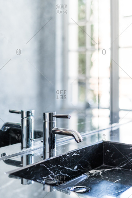Rectangular washbasin and shiny steel faucet in luxurious bathroom in daylight