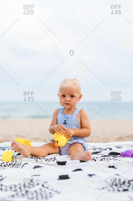 Portrait of baby boy playing with rubber ducks on the beach