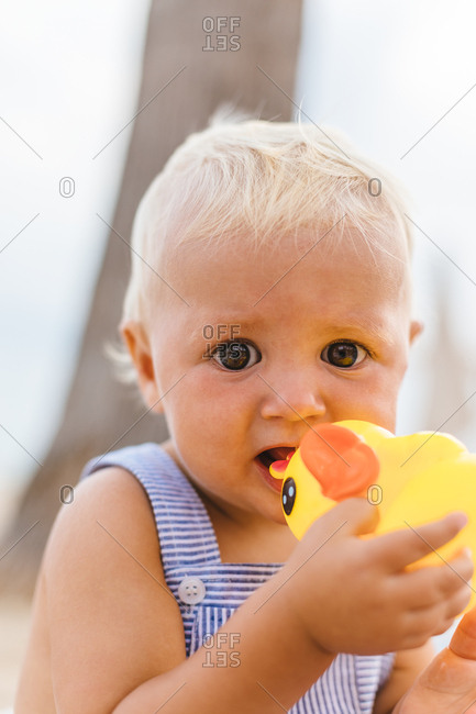 Portrait of baby boy playing with rubber ducks on the beach