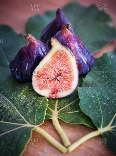 chopped fig and figs over wooden table with green leaves