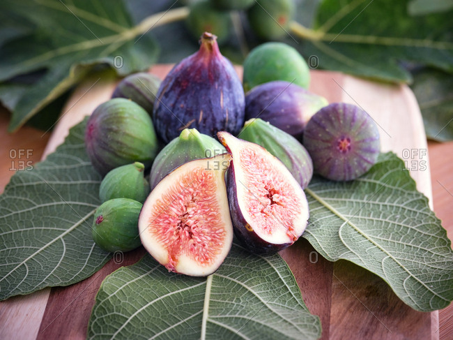chopped fig and figs over wooden table with green leaves