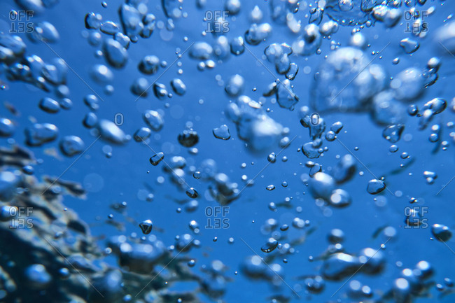 Background of oxygen bubbles rising up to surface of sea in clear and transparent water