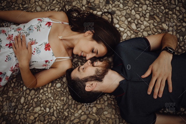 Side view of loving casual man and woman lying on stone parapet of viewpoint at majestic hazy valley