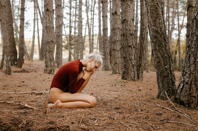 Beautiful modern woman resting barefoot in evergreen forest